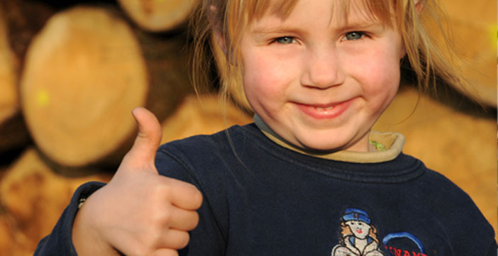Kind lächelt vor Holzstioß