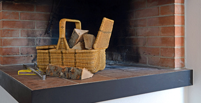 Holzkorb mit Brennholz in Kamin